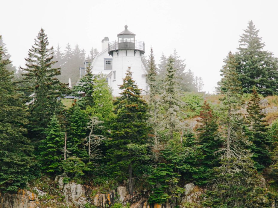 white lighthouse sitting on a brown and green cliff